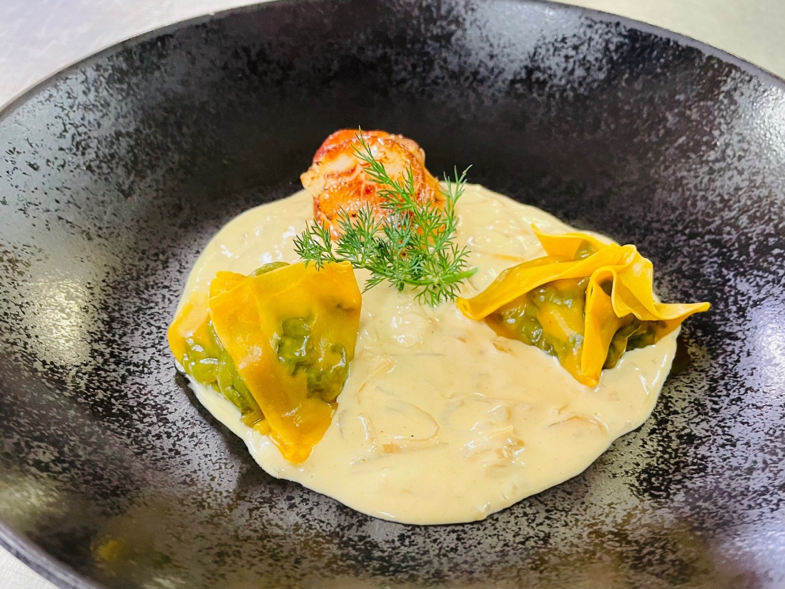 Ravioles de pousses d'épinards, noix de Saint-Jacques snackées dans une crème de moules.